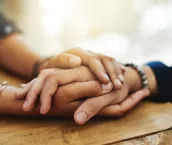 Cropped shot of two people holding hands in comfort