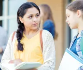 Serious teenage girls discuss an upcoming exam as they wait for school to start