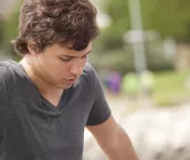 Young man sitting by himself and looking sad