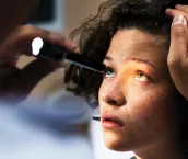 A youg girl having her eyes examined by a medical doctor