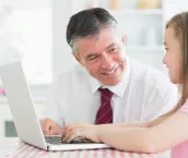 Man smiling at child using a laptop