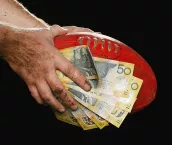 Hands holding football and money.