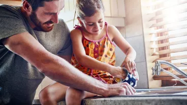 Man with child washing dishes