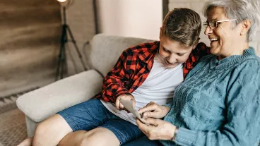 Multi-generation family having good time in living room, showing memories from past