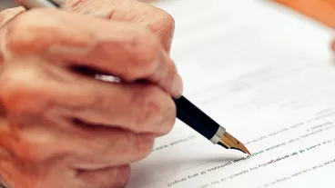 Close up of a senior person filling in a paper form