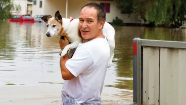 Man holding a dog on his shoulders as he stands in waist deep flood waters. Man holding a dog on his shoulders as he stands in waist deep flood waters.