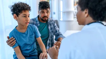 A biracial boy with his father being examined by a paediatrician.