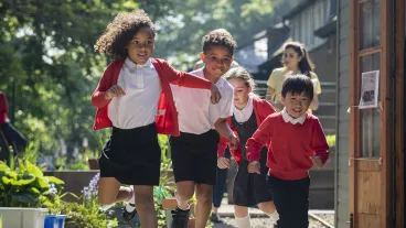 A group of school children running in the school yard as they head to playtime. Two of the children are siblings and go to the same school in Hexham in the North East of England.