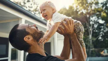 Shot of a father playing with his baby boy while standing outside his house