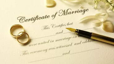 Closeup of a Certificate of Marriage, pen and wedding rings.