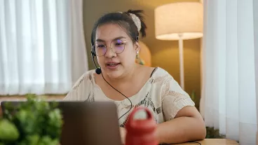 Transgender woman using laptop for conference call, working from home concept.