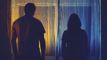 Silhouette of sad man and woman in a quarrel against the background of a night window. Divorce of husband and wife in the evening light of the home living room