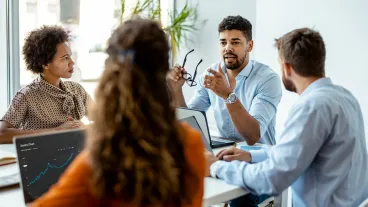 Confident and successful team. Group of young modern people in smart casual wear discussing business while sitting in the creative office.
