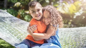 First Nations Australian siblings hugging in the garden on a sunny day.