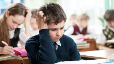 Schoolboy sitting at the classroom and working hardly