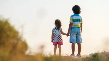 Portrait of female toddler holding hands with a little boy looking into the distance