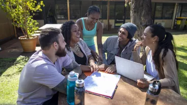 Young aboriginal students sitting together and studying outdoors in the sun in Australia