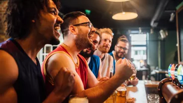 Happy young people watching game on TV in the bar