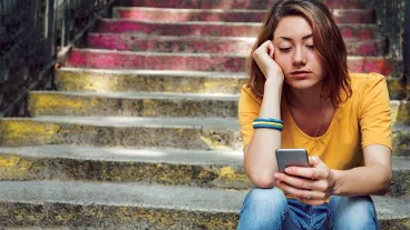 Teen girl dressed in yellow t-shirt breaking up with his boyfriend through messages. Dark toning.