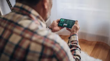 Elderly man uses smartphone for sports betting from home