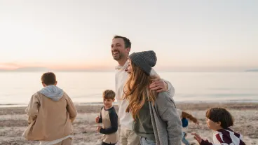 Photo of a young family, having a relaxed walk down the beach by the ocean Photo of a young family, having a relaxed walk down the beach by the ocean