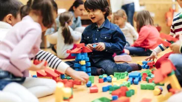 Group of children playing with blocks in kindergarten. Showing their imagination and skill and creativity. Selective focus to little boy building with blocks.