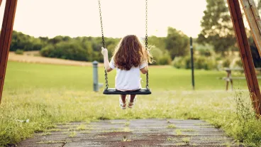 Rear view of child sitting on swing in a playground