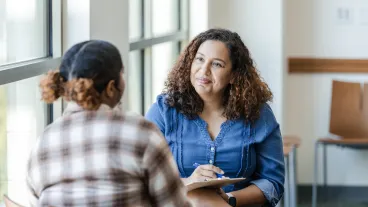 An unrecognizable young adult female college student shares her struggles with the cheerful mid adult female counselor.An unrecognizable young adult female college student shares her struggles with the cheerful mid adult female counselor.
