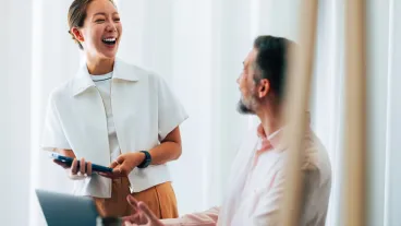 A cheerful interaction between colleagues showcasing teamwork, collaboration, and positive workplace dynamics within a contemporary office environment.
