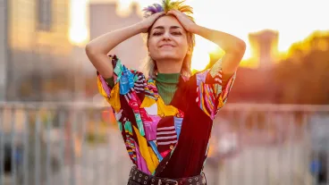 Portrait of beautiful non-binary person standing on city street at sunset.