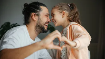 Father and cute little child daughter showing love sign.