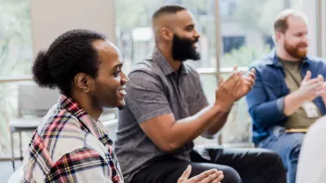 Diverse men applaud and encourage unseen group member