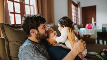 Father playing with toddler on the sofa