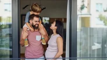 Happy Asian pregnant woman talking to her family while spending their time together on a balcony.