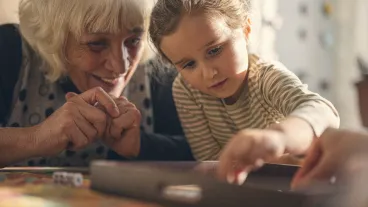 Multigenerational family get together, grandma, mom and child play chinese checkers in cozy home with warm light, creating loving atmosphere.