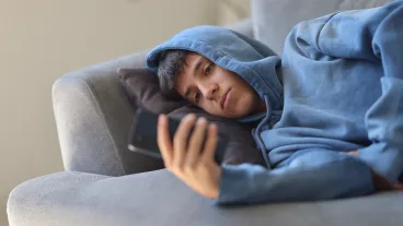  Teenage Boy with Smartphone Relaxing on Living Room Sofa