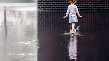 Young girl walking in a puddle of water barefoot