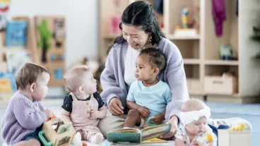 A nurturing caregiver engages young children with a story in a vibrant playroom, fostering learning and interaction. The scene highlights fun, diversity, and early education development through shared activities.
