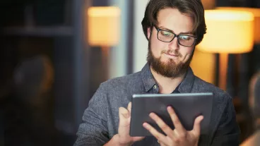 Shot of a young businessman using a digital tablet during a late night at work Shot of a young businessman using a digital tablet during a late night at work