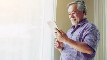 Senior man reading on this tablet at home