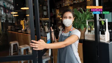 Happy business owner opening the door at a cafe wearing a facemask to avoid the spread of coronavirus