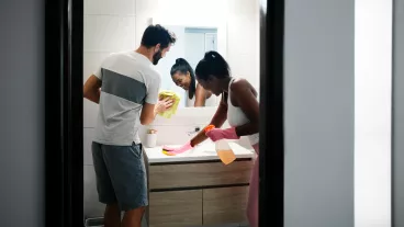 Multi-ethnic couple doing chores cleaning home bathroom