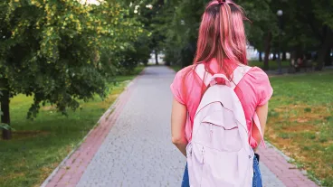Rear view of a girl at green park. She has pink colored hair and shirt and wearing blue jeans