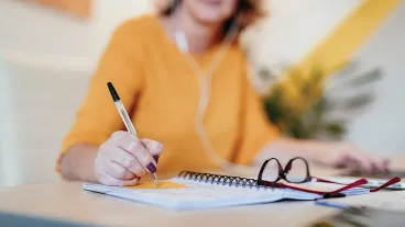 Mature woman working from home dressed in yellow and attending video conference meeting 