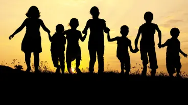 Silhouette, group of happy children playing on meadow, sunset, summertime
