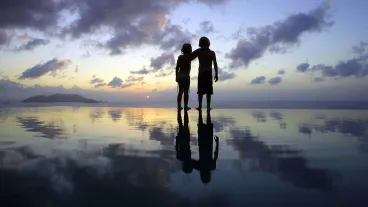 Children standing on beach at sunset
