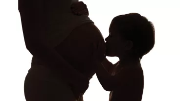 Happy family. Silhouette of toddler kissing belly of pregnant mother
