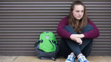 Homeless teenage girl on streets with green rucksack