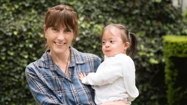 Mature woman carrying her little girl with down syndrome