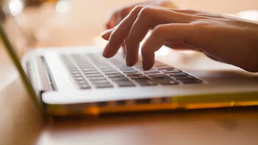 Close up of a woman tying on a laptop